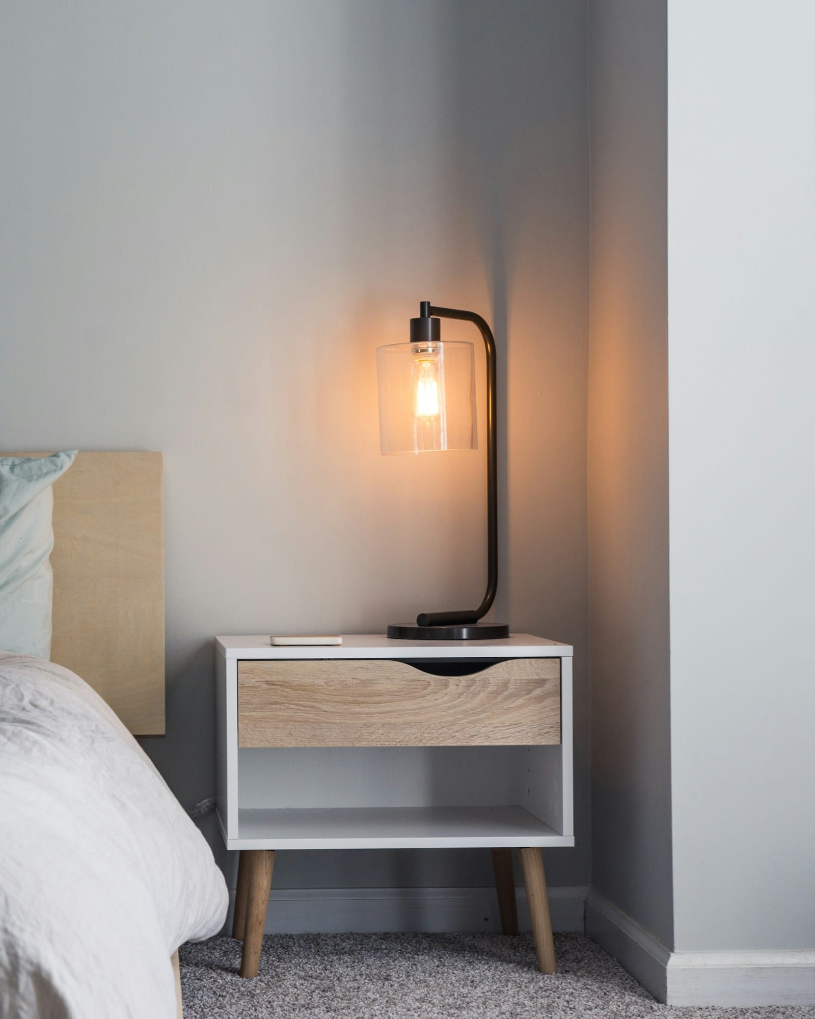 The main bedroom in white and pale grey, with a bench at the foot of the bed