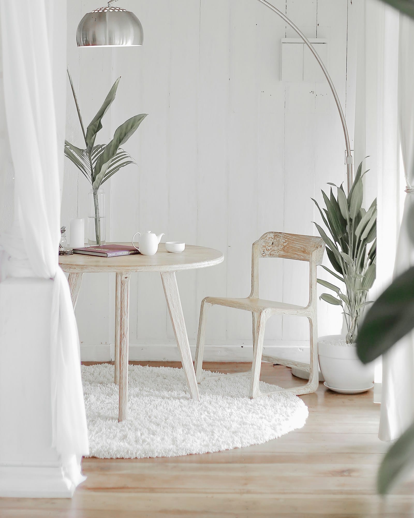 A quiet corner with a light timber chair, sheer curtain and trailing greenery